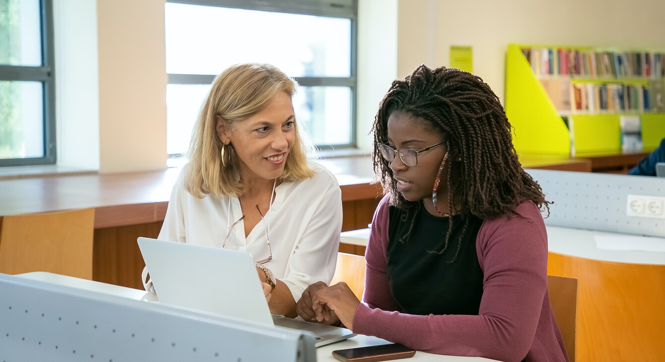 Une professeure échange avec une élève devant un ordinateur