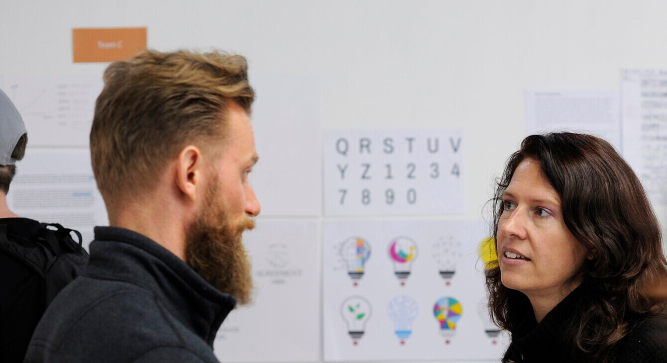 Un homme et une femme discutent devant un tableau blanc