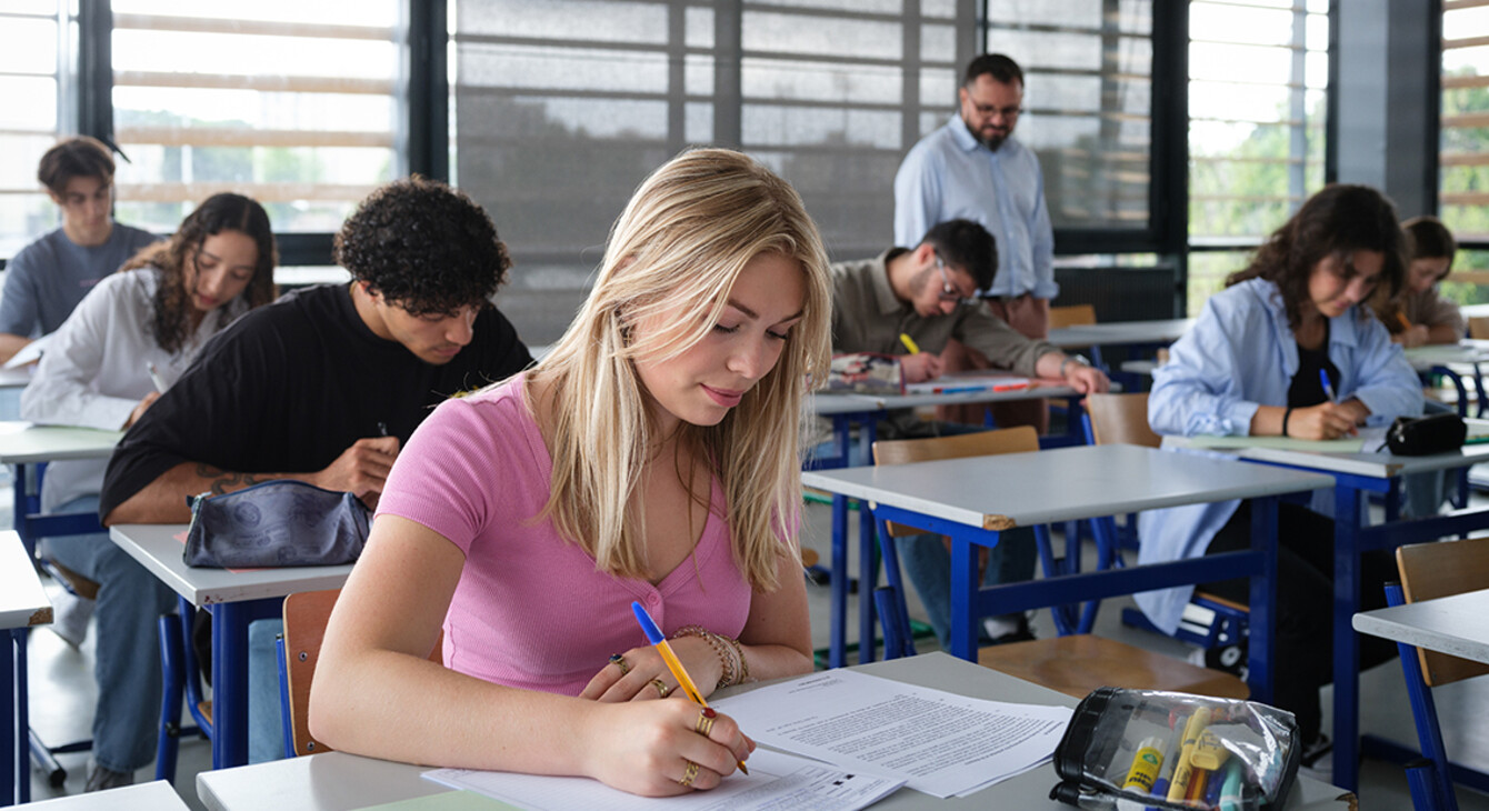 Une classe passe les épreuves écrites du bac, avec une jeune fille au premier plan.