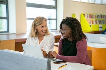 Une professeure échange avec une élève devant un ordinateur