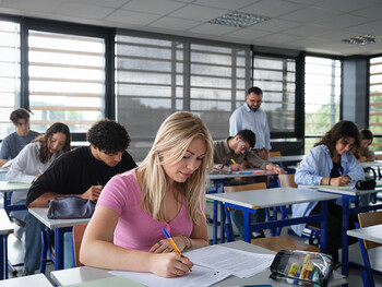 Une classe passe les épreuves écrites du bac, avec une jeune fille au premier plan.