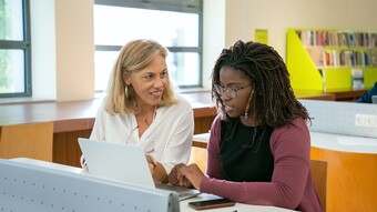 Une professeure échange avec une élève devant un ordinateur