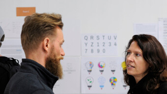 Un homme et une femme discutent devant un tableau blanc