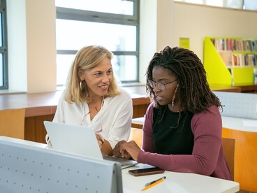 Une professeure échange avec une élève devant un ordinateur