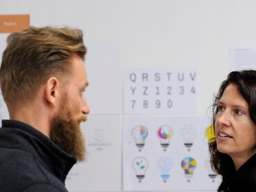 Un homme et une femme discutent devant un tableau blanc